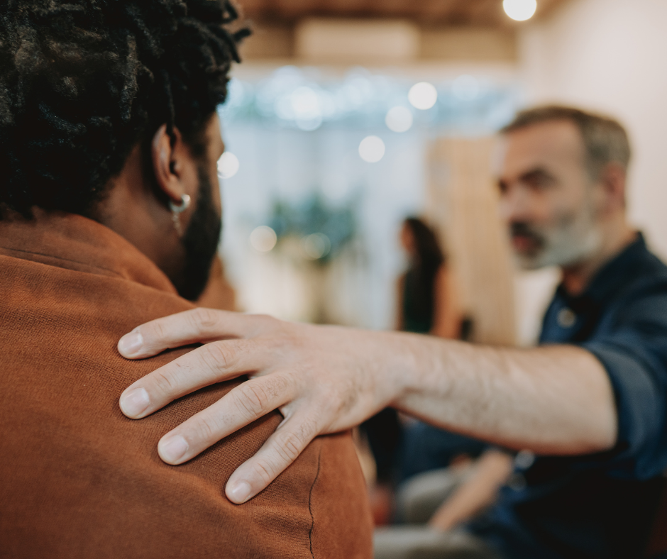 Man offering support with a hand on another persons shoulder