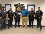 SLVFB employees presenting a We Care, We Share donation to Alamosa Police Department Shop with a Cop