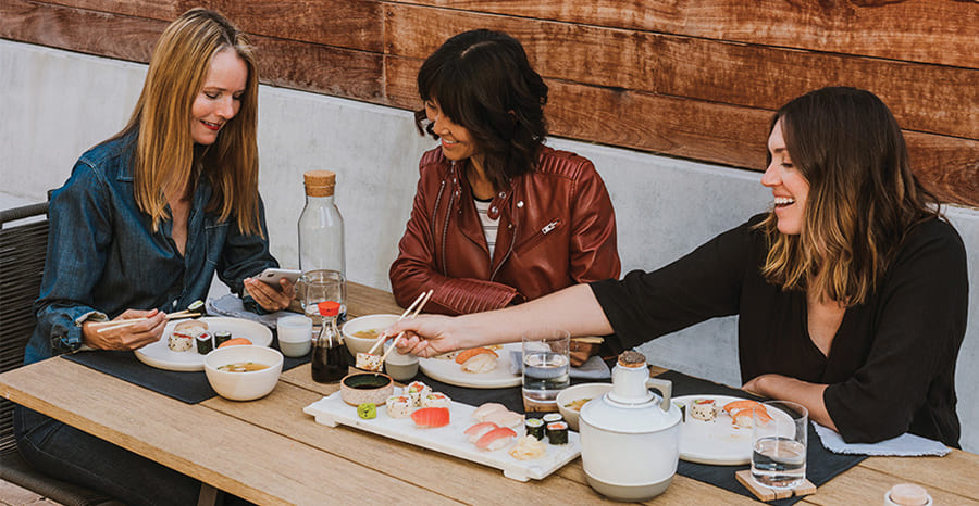 group of women on mobile phone eating sushi